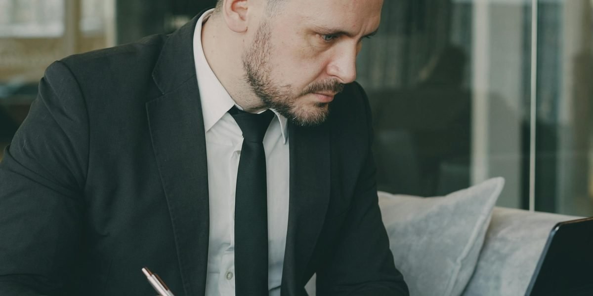 Person reviewing AI output on laptop while taking notes